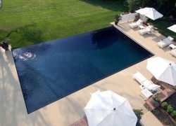 Offering pool construction services: an aerial view of a swimming pool with lounge chairs and umbrellas.